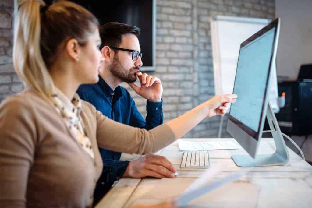 man-and-woman-coworkers-collaborating-at-desk-with-computer-monitor-and-keyboard