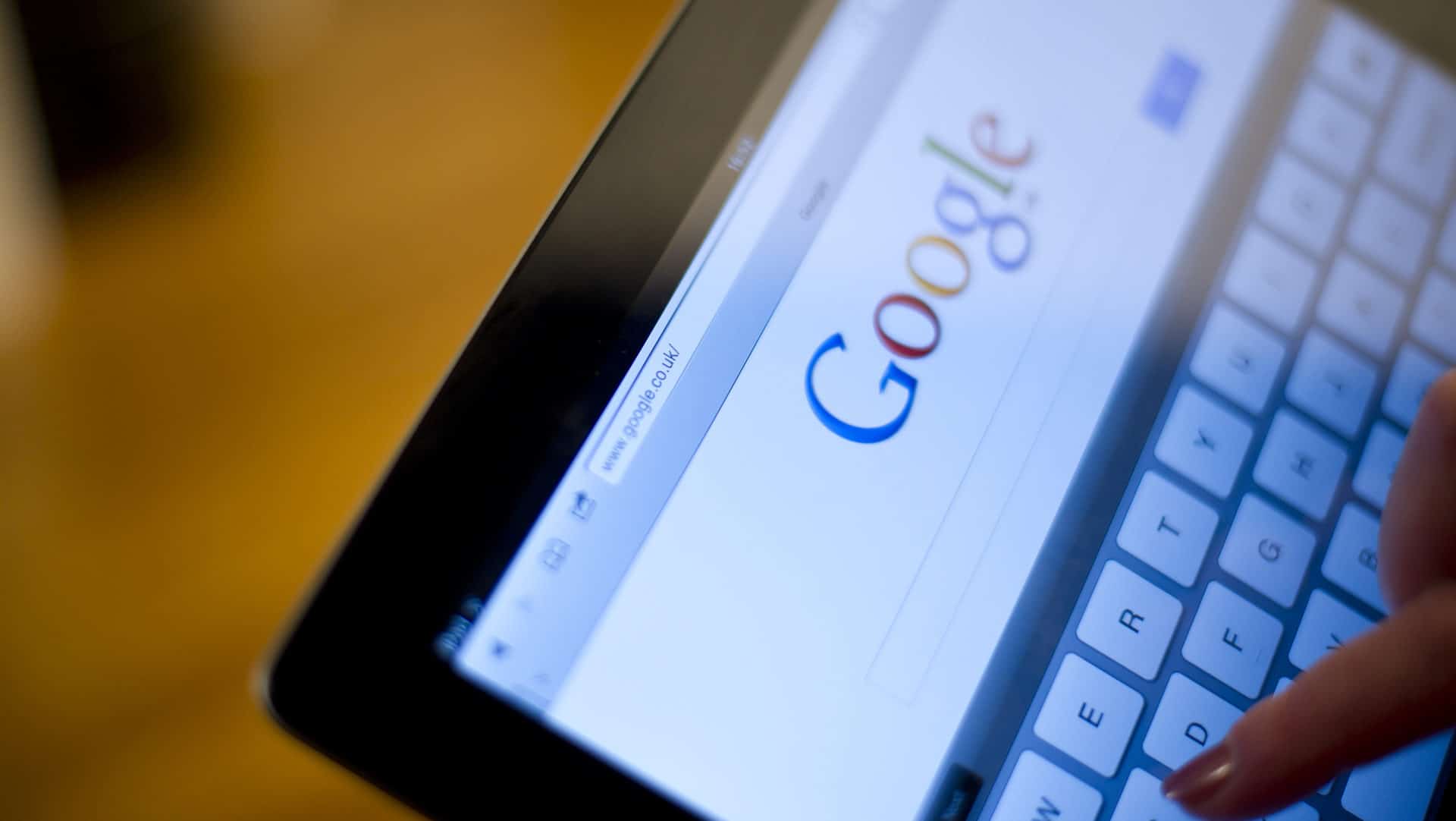 A tablet displaying the google search page after core updates with a finger touching the pop-up keyboard