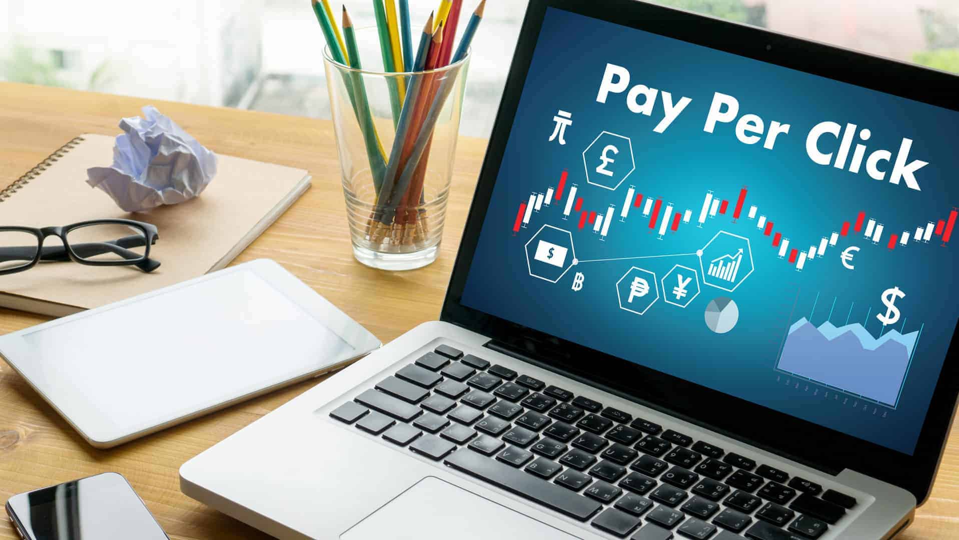 laptop-displaying-ppc-advertising-data-on-desk-with-phone-notebook-and-pencil-cup