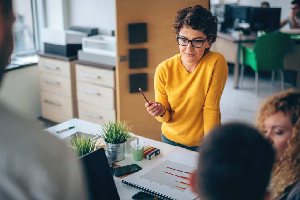 woman-giving-informal-presentation-about-digital-marketing-myths-in-office-with-desks-and-filing-cabinets-in-background